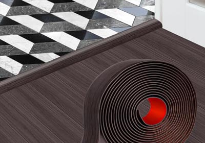 Close-up of a self-adhesive door threshold strip installed on flooring